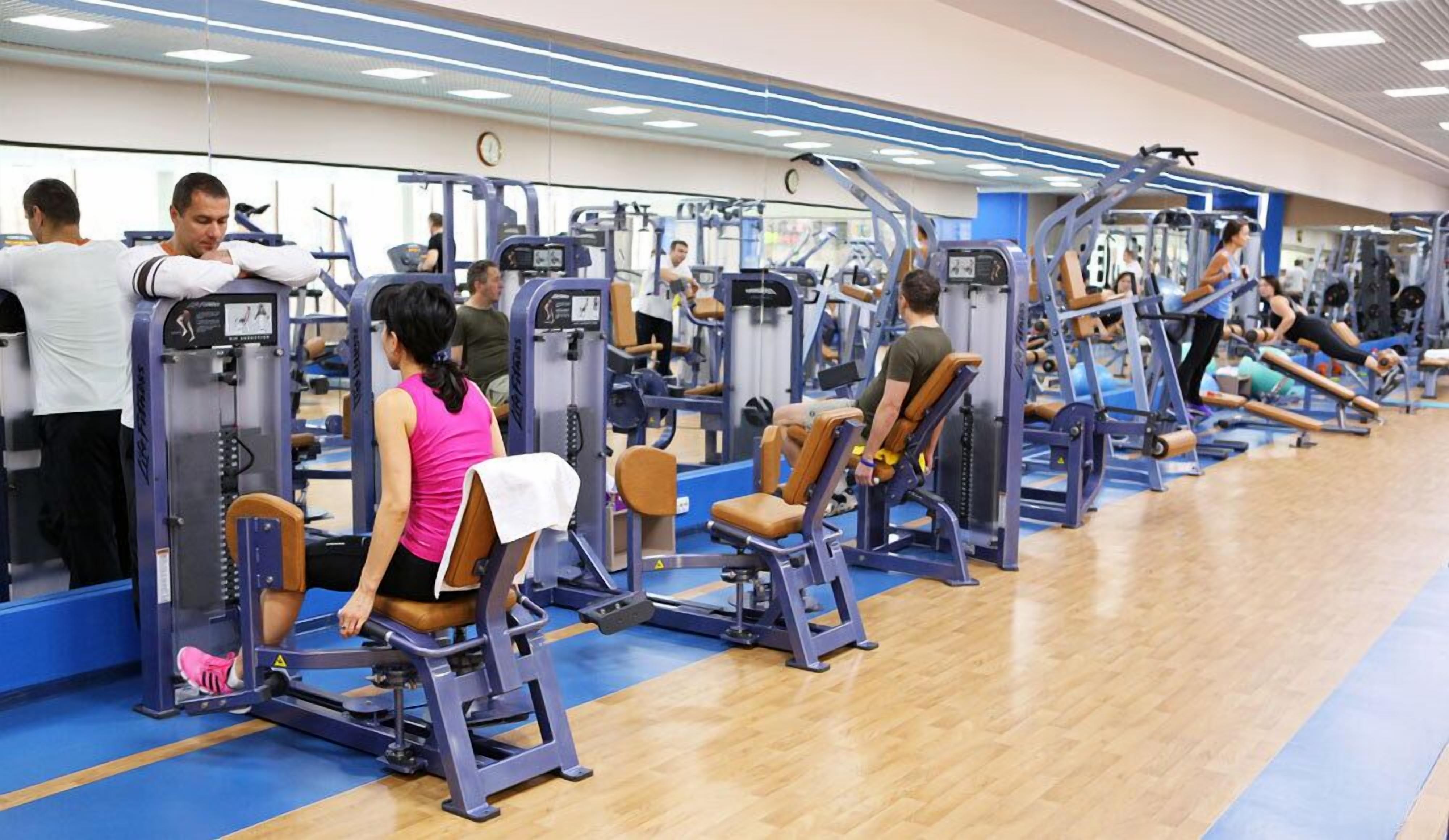 Un gimnasio con diferentes máquinas de ejercicio y suelo azul.