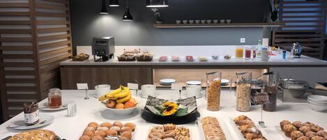 A breakfast buffet with various pastries, fruits, and beverages.