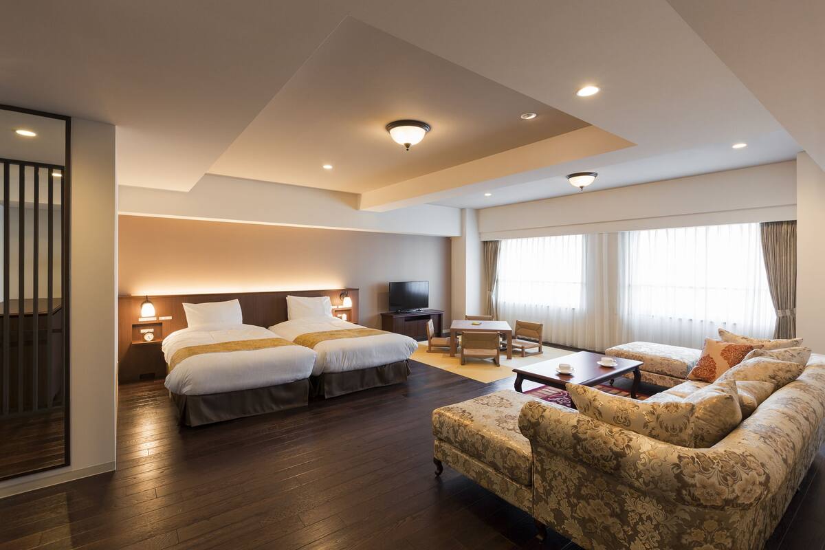 Una habitación de hotel con una cama grande, un sofá, un televisor y un escritorio.
