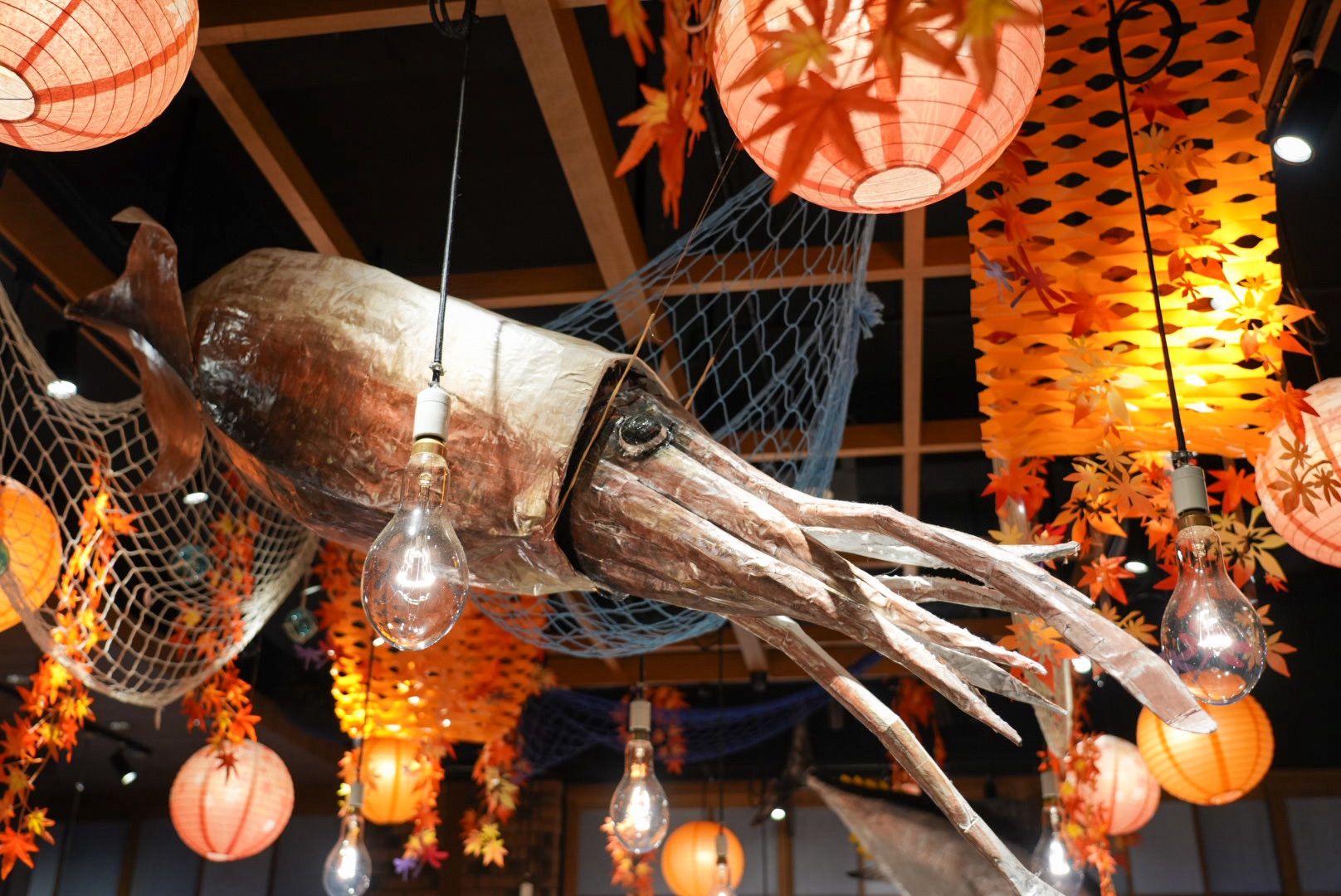 A decorative fish sculpture with hanging light bulbs and paper lanterns.