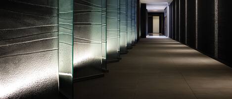 A modern hallway with glass partitions and a tiled floor.
