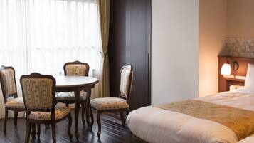 A hotel room with a bed, a round table with four chairs, and a nightstand with a lamp.