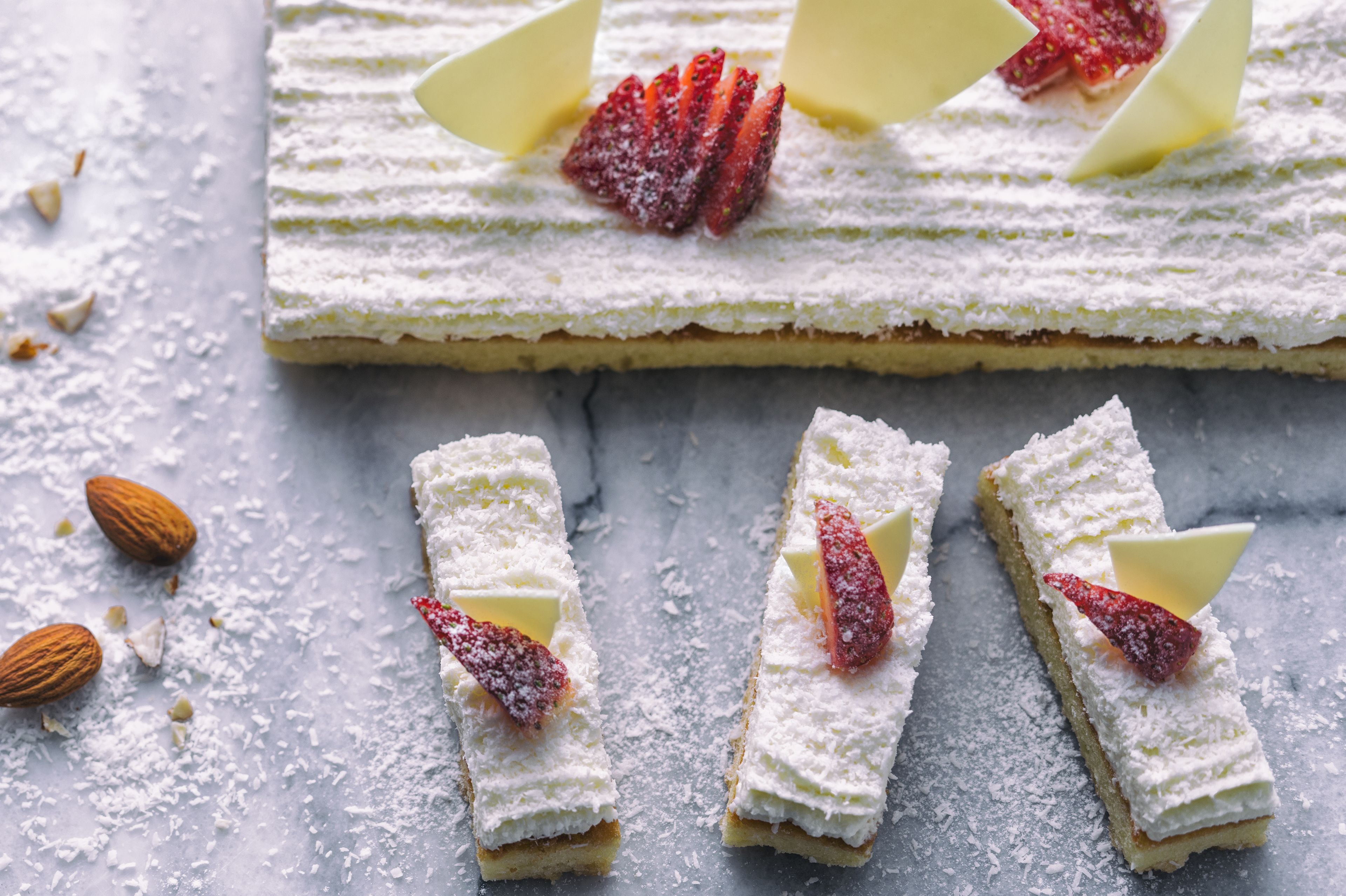 Un dessert saupoudré de sucre glace et garni de fraises, présenté sur une surface en marbre.
