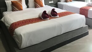 Une chambre d’hôtel avec deux lits, une couvre-lit rouge et blanche, et deux appliques murales.