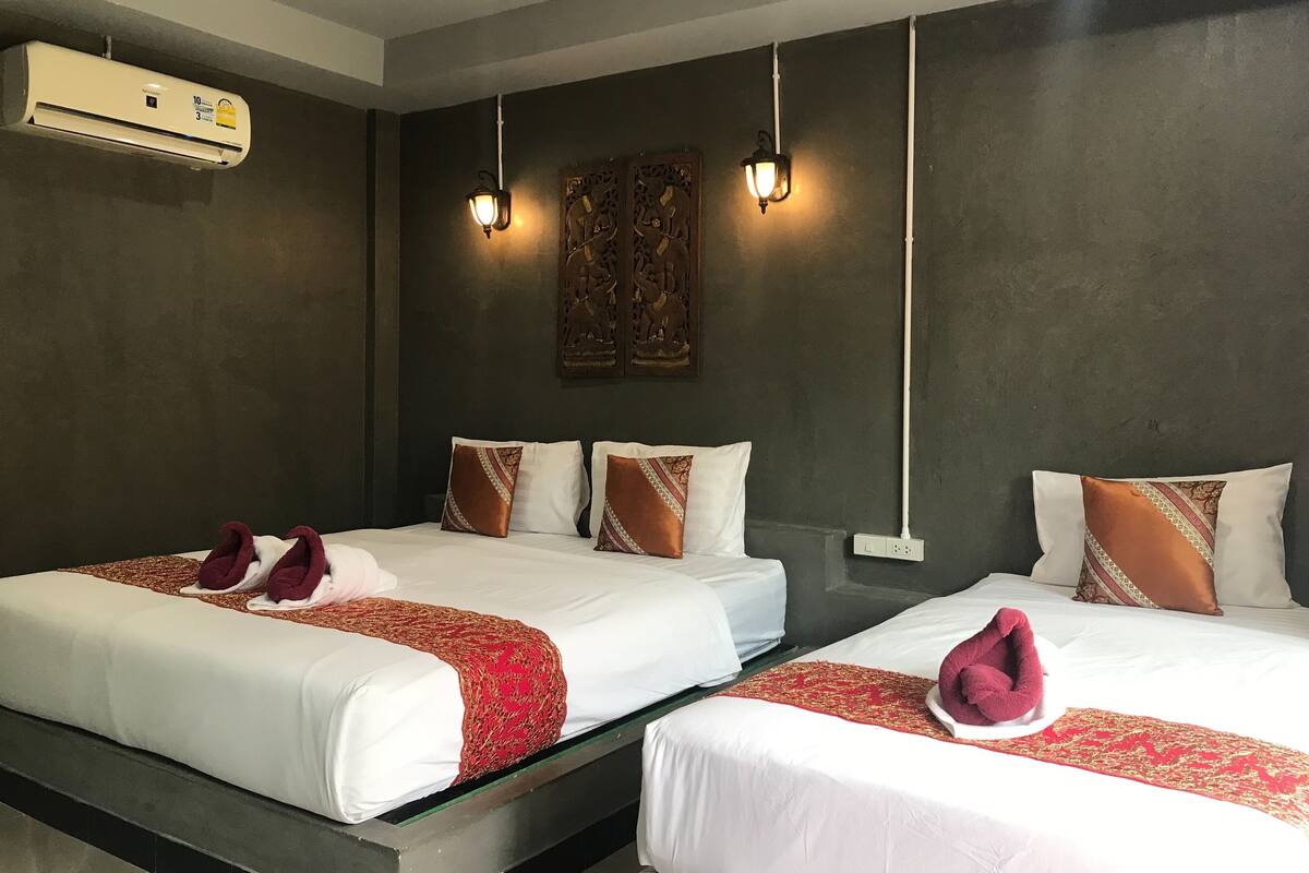 Two double beds with white linens, red decorative pillows, and a red patterned throw.