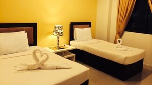 Quarto de hotel com duas camas de solteiro, mesa de cabeceira com luminária e janela com cortinas.