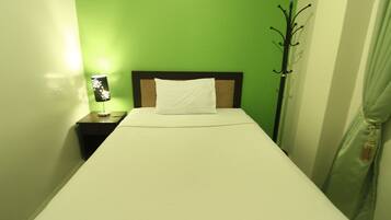 A single bed with white bedding in a room with green walls.