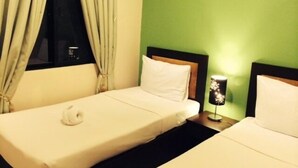 Quarto de hotel com duas camas de solteiro, mesa de cabeceira com abajur e janela com cortinas.