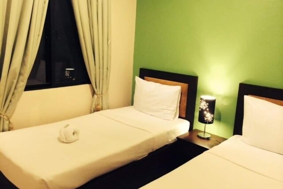 Une chambre d’hôtel avec deux lits simples, une table de chevet avec une lampe et une fenêtre avec des rideaux.