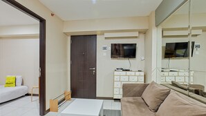 A modern hotel room with a sofa, a small table, a TV, and a minibar. - Literooms At Kebagusan City (Jakarta)