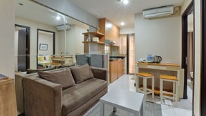 A compact living space with a sofa, a coffee table, a kitchenette, and a small dining area. - Literooms At Kebagusan City (Jakarta)