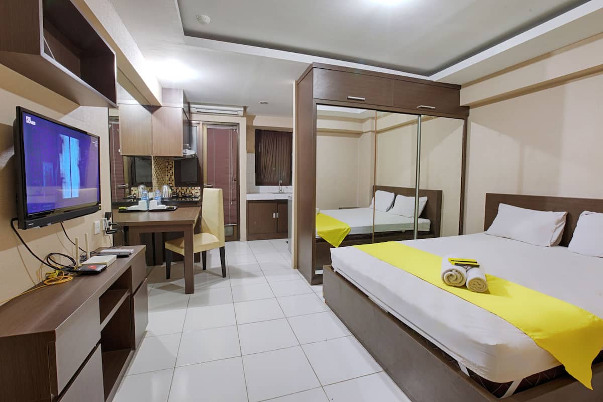 Une chambre d’hôtel avec un lit, un bureau équipé d’un ordinateur, une télévision et une salle de bain visible à travers une porte ouverte.