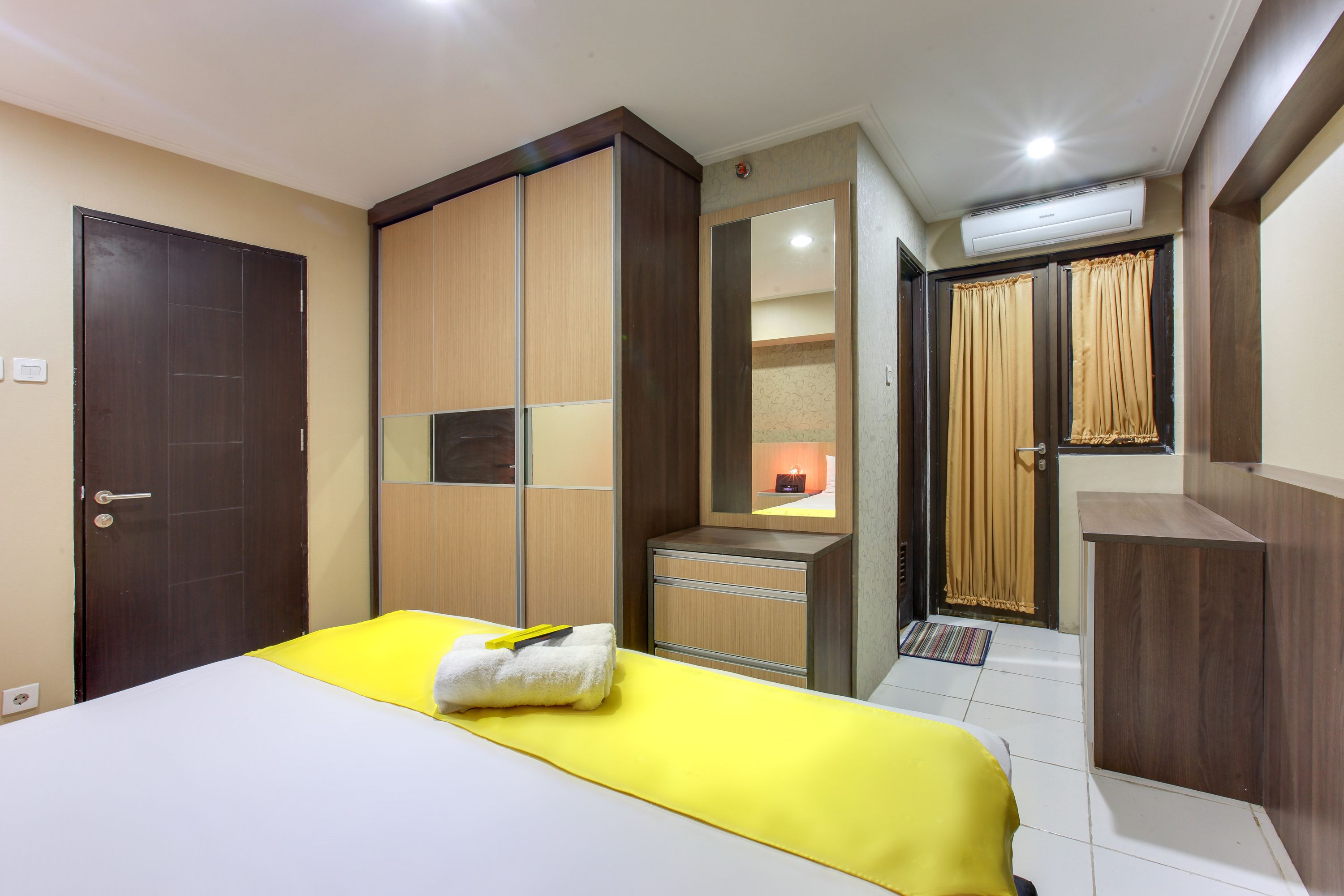 Une chambre d’hôtel avec un lit, une armoire, un bureau et un miroir.