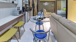 A compact living space with a kitchenette, a sofa, and a dining area. - Literooms At Kebagusan City (Jakarta)