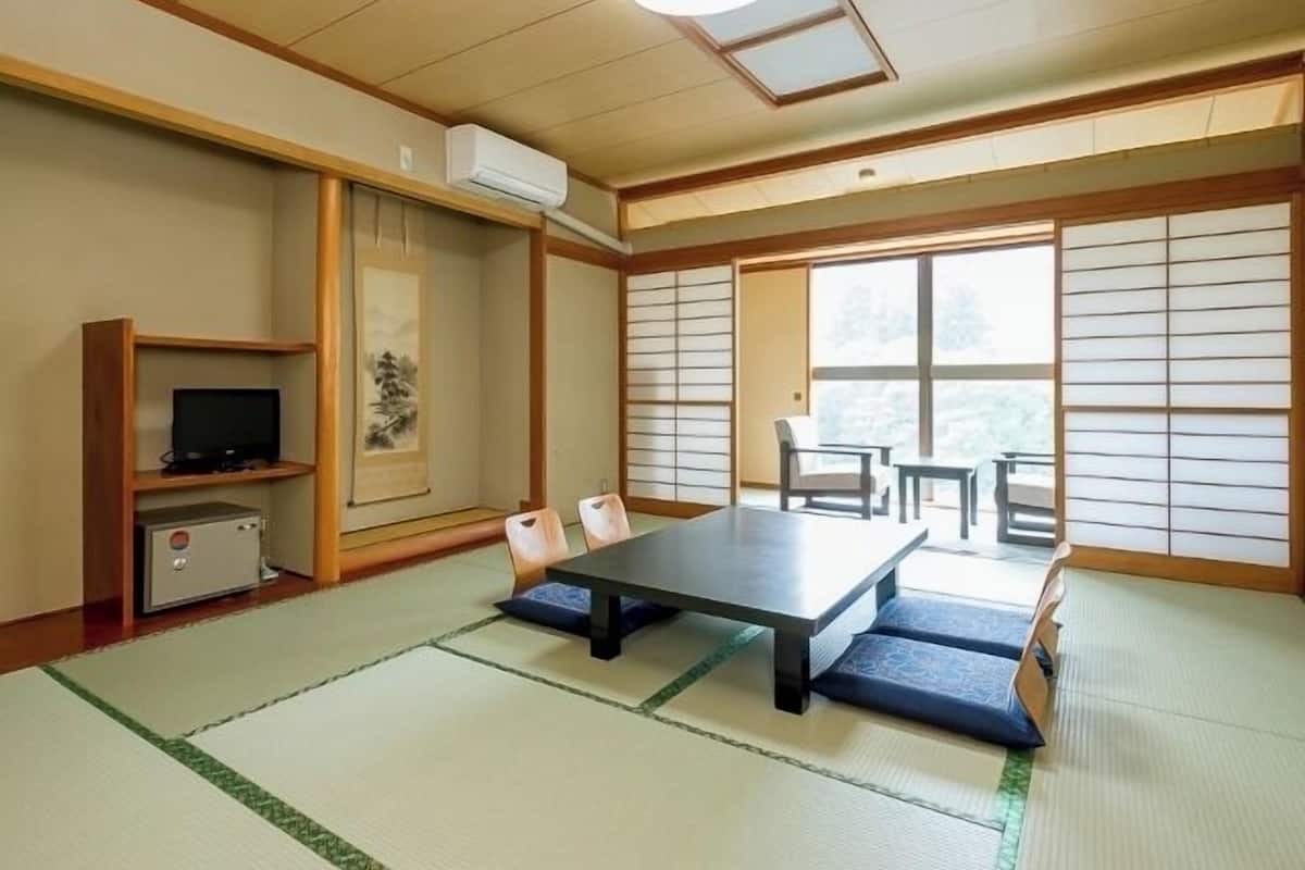 Ett traditionellt japanskt rum med tatamimattor på golvet, ett lågt bord, stolar, en tv och en värmare.
