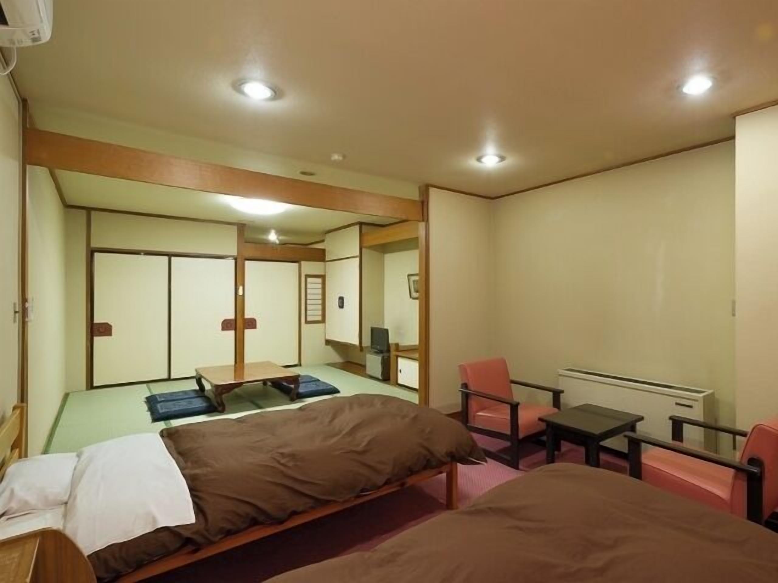 Quarto com cama, escrivaninha, cadeira e televisão.