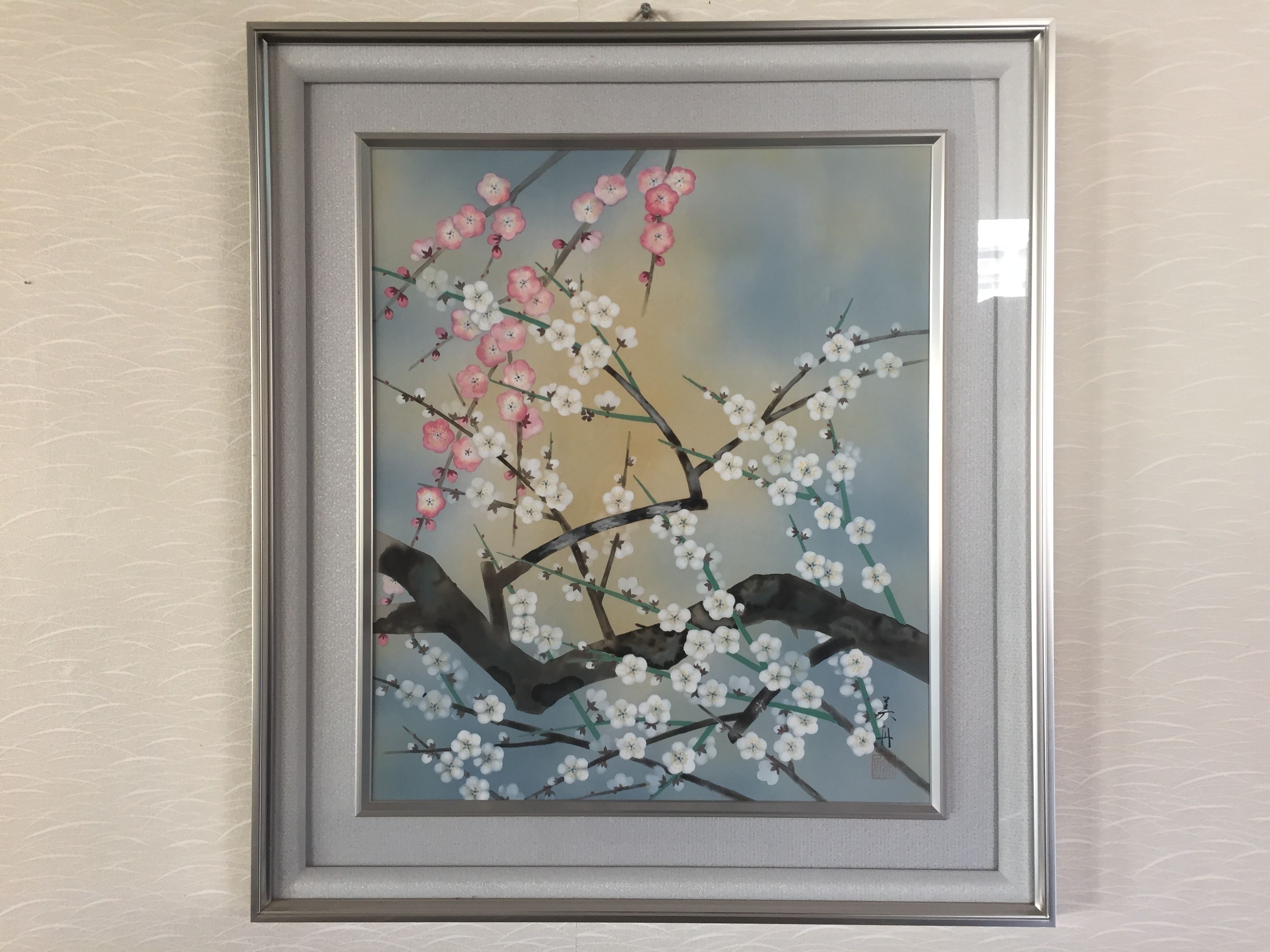 A framed artwork of a tree branch with pink and white blossoms.