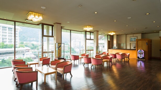 Un hall d’hôtel spacieux, doté de grandes fenêtres, d’un parquet en bois et de mobilier moderne.