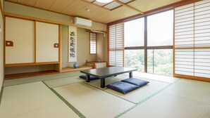 Une pièce de style japonais traditionnel, avec un sol recouvert de tatamis, une table basse, des portes coulissantes et une vue sur la verdure.