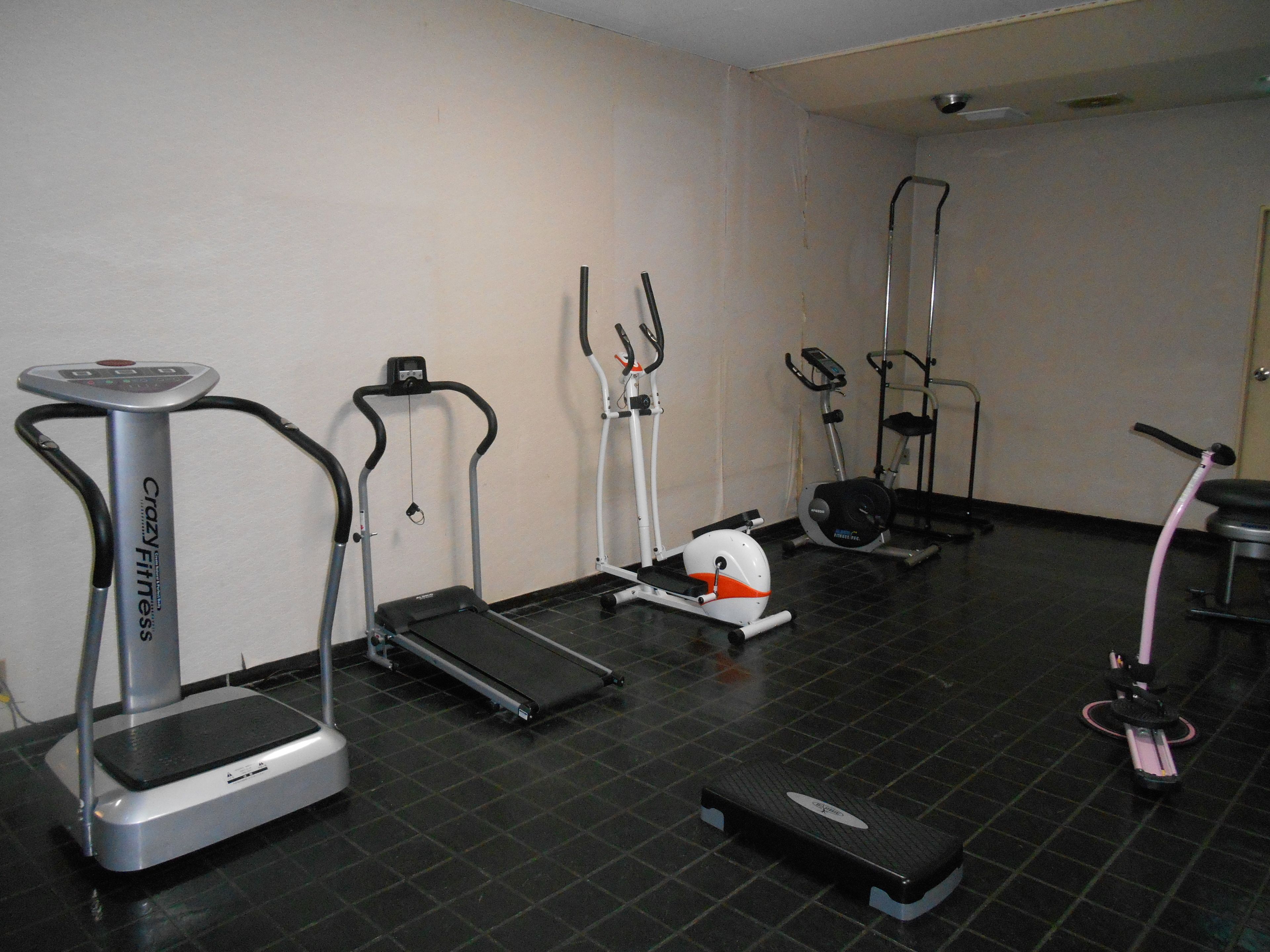 A fitness room with various exercise equipment including treadmills, an elliptical, and a stationary bike.