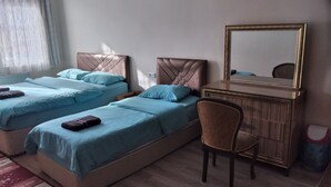 Ein Hotelzimmer mit zwei Betten, einem Holzkoffer mit Spiegel und einem Sessel.