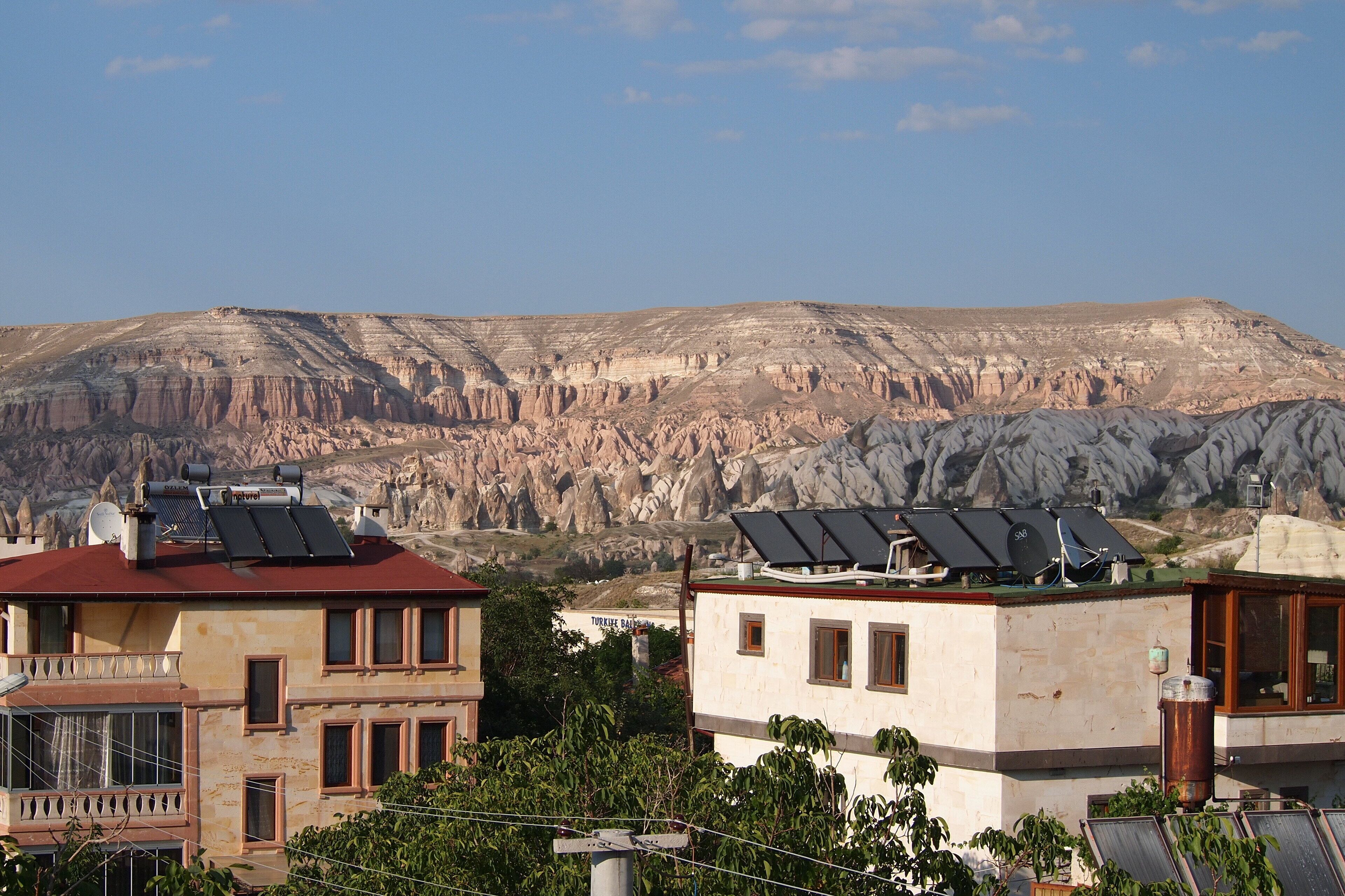 A building with solar panels on the roof, a balcony, and a view of a rocky landscape.