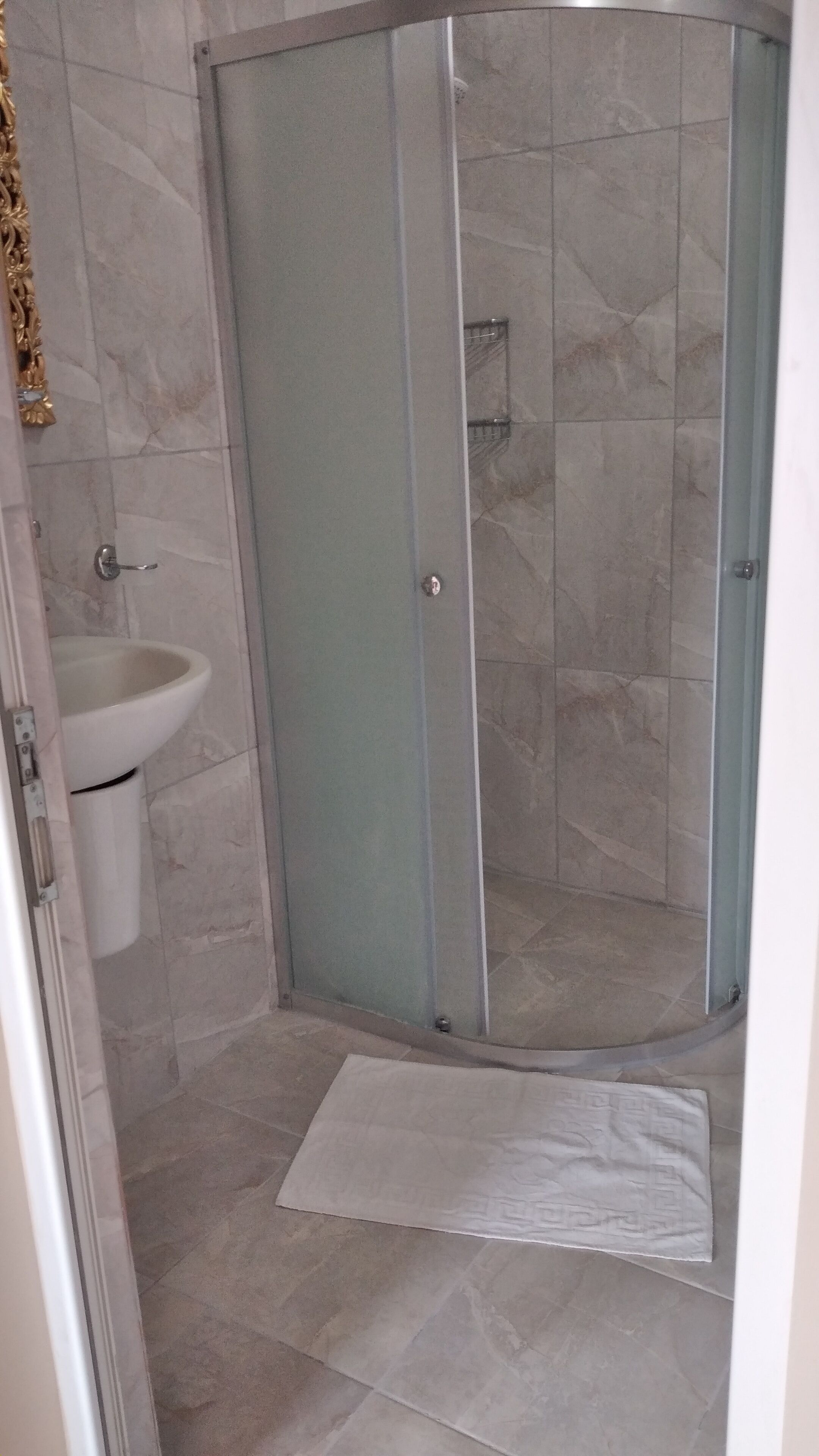 A shower area with a glass door, a sink, and a towel on the floor.