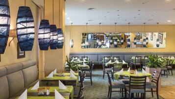 A restaurant with multiple tables, chairs, and a seating area with a sofa.