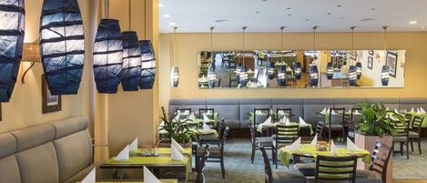 Un restaurant doté de plusieurs tables, de chaises et d’un espace salon avec un canapé.
