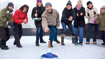A group of people on an ice rink, some holding curling stones.