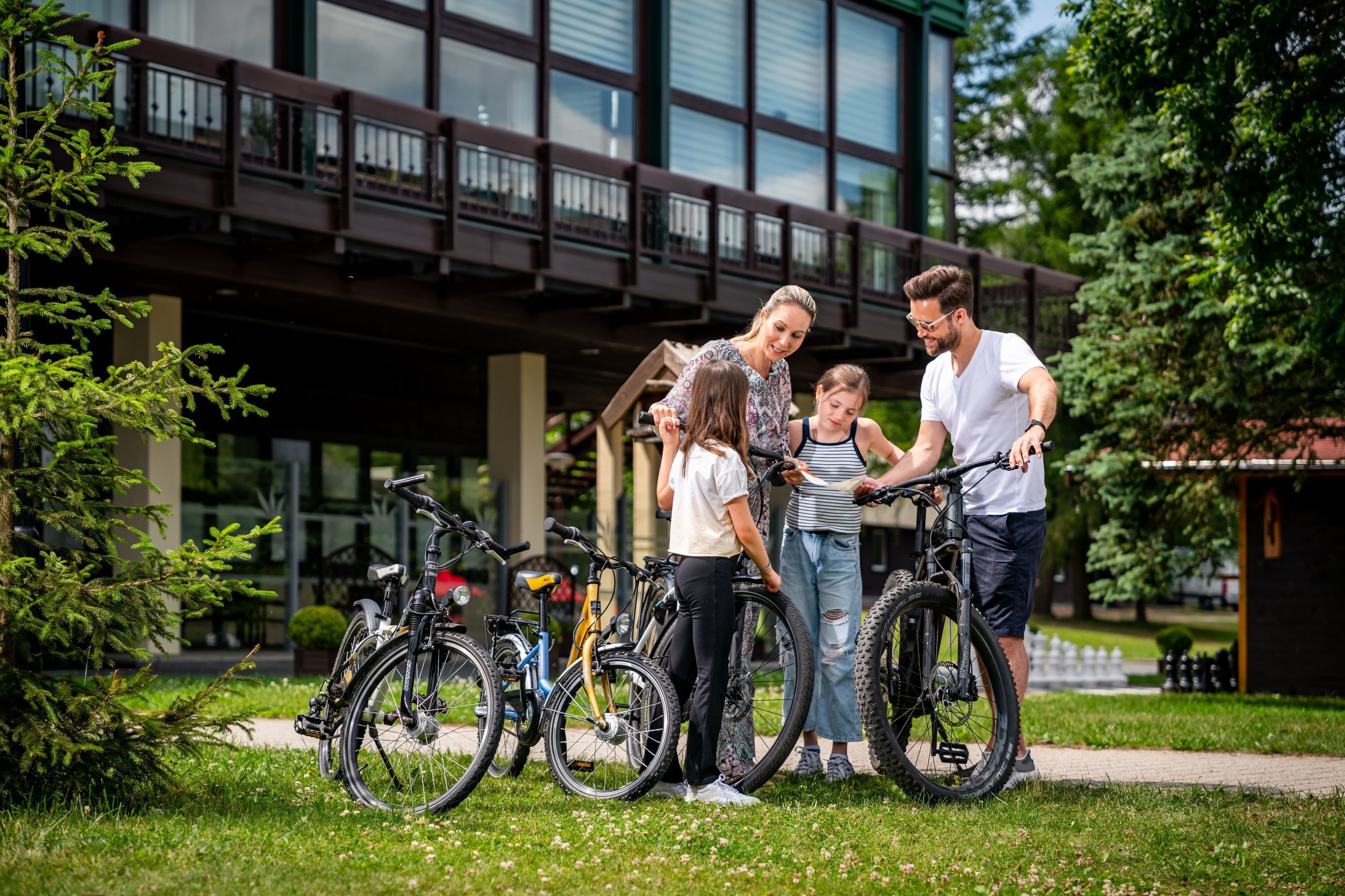 Een groep mensen staat buiten bij fietsen, met een modern gebouw en een brug op de achtergrond.
