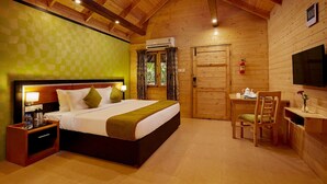 A wooden-paneled room with a bed, bedside table, chair, desk, and a television. - Sterling Anaikatti (Mannarkkad)
