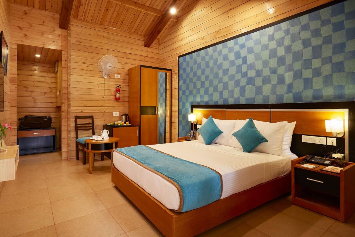 A wooden-paneled room with a bed, bedside table, and a small table with a chair.