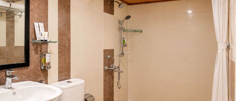 A bathroom with a sink, toilet, shower, and a mirror.