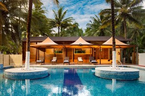 A pool area with two circular water features, lounge chairs, and umbrellas. - Sterling Anaikatti (Mannarkkad)