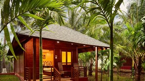 A wooden cabin with a porch, surrounded by lush greenery and palm trees. - Sterling Anaikatti (Mannarkkad)