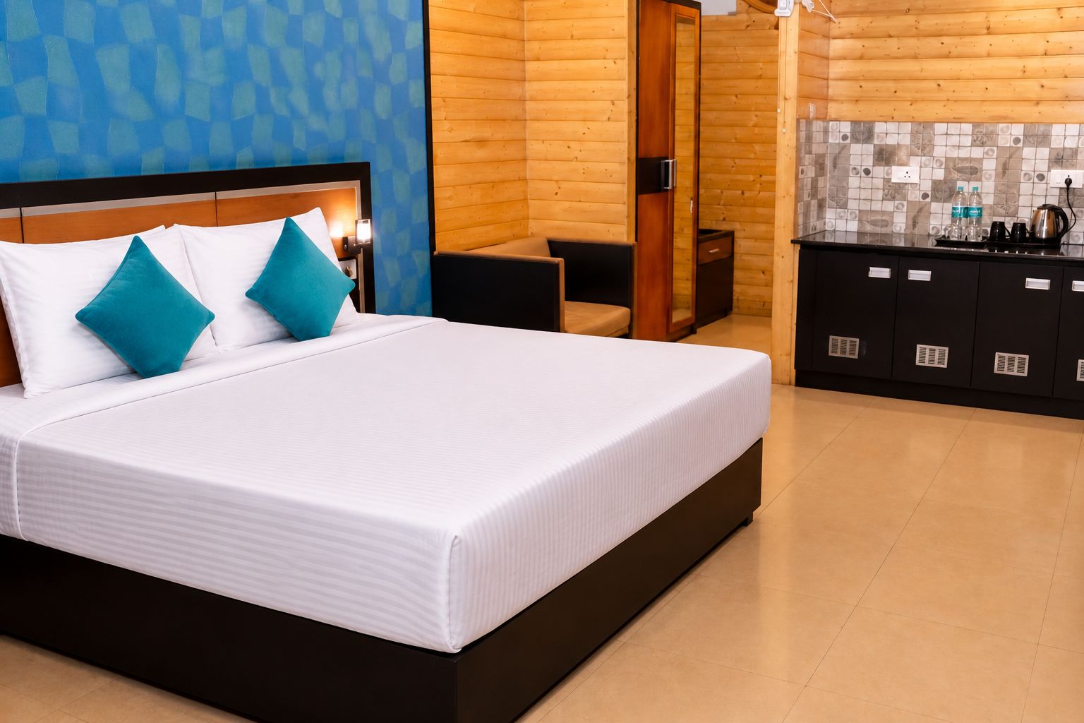 A hotel room with a large bed, a wooden wardrobe, and a bathroom with a wooden door.