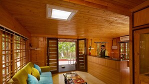 A wooden interior with a reception desk, a sofa with cushions, and a coffee table. - Sterling Anaikatti (Mannarkkad)