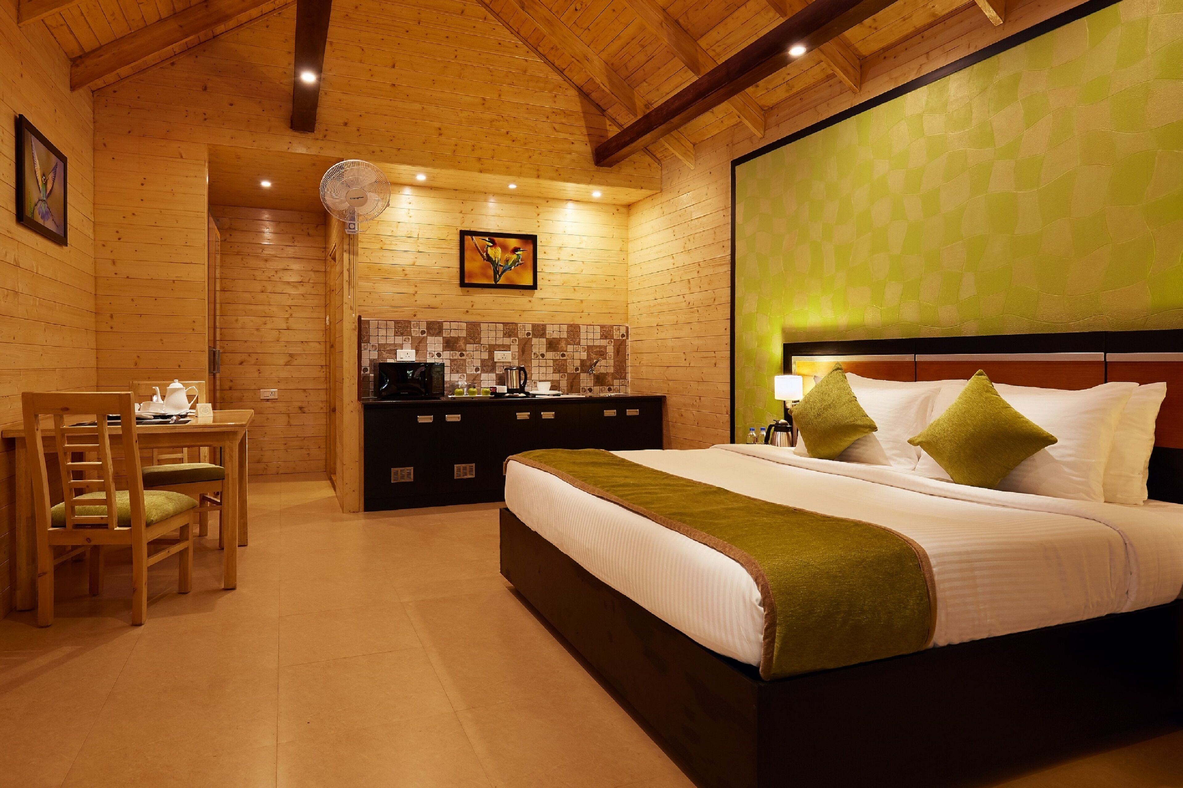 A wooden room with a bed, a desk, and a kitchenette.