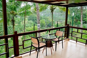 A balcony with a table and chairs, overlooking a lush green landscape with palm trees. - Sterling Anaikatti (Mannarkkad)