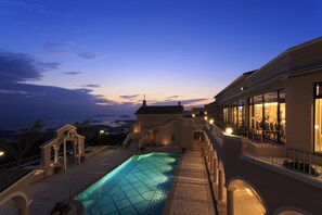 A swimming pool with a geometric pattern, a building with a balcony, and a view of the landscape. - Yumihari No Oka Hotel (Sasebo)
