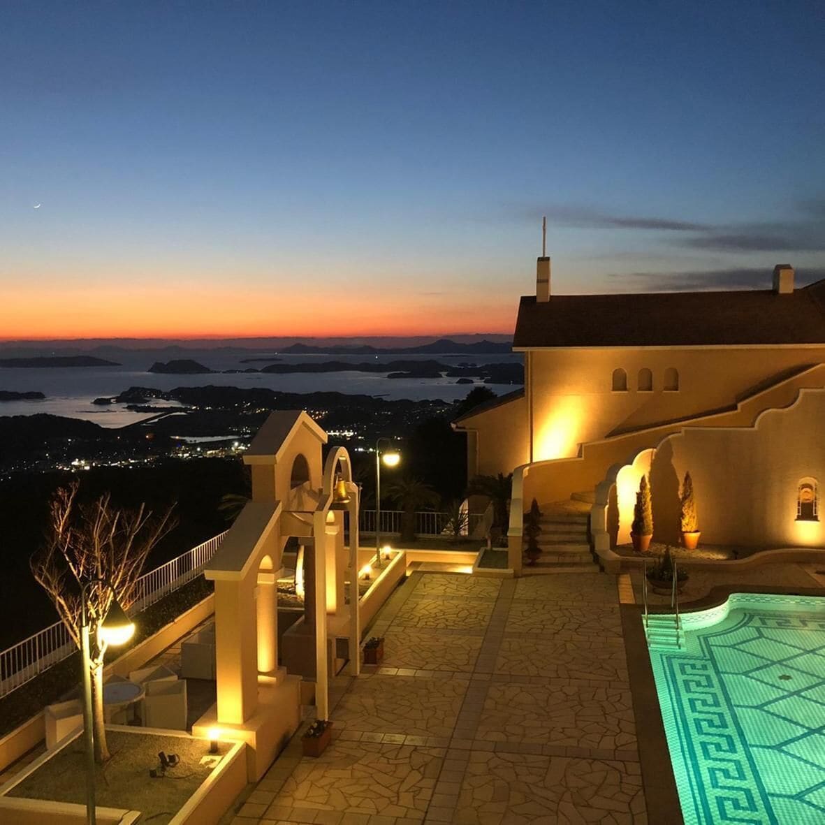 A pool area with a view of the sea at dusk.