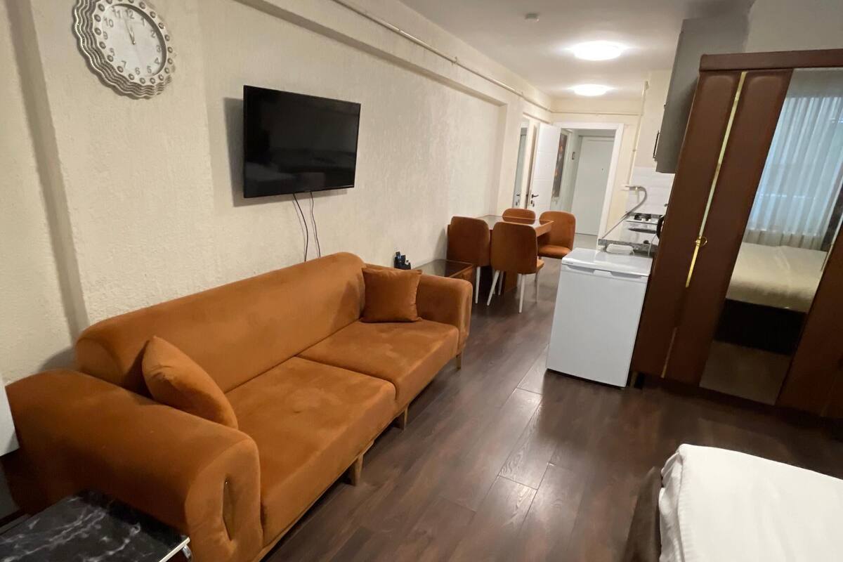 A hotel room with a sofa, a TV, a small table, and a bed.