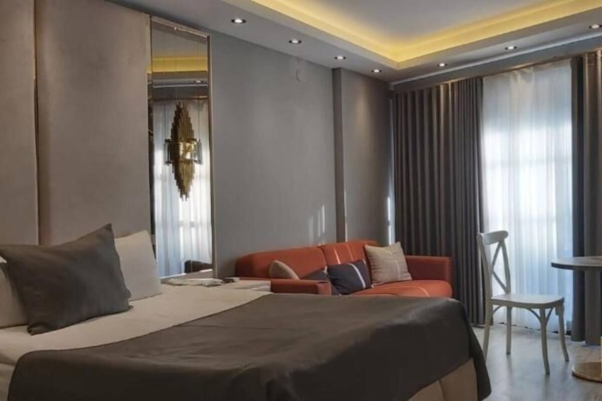 A hotel room with a large bed, a sofa, a small table, and a chair.