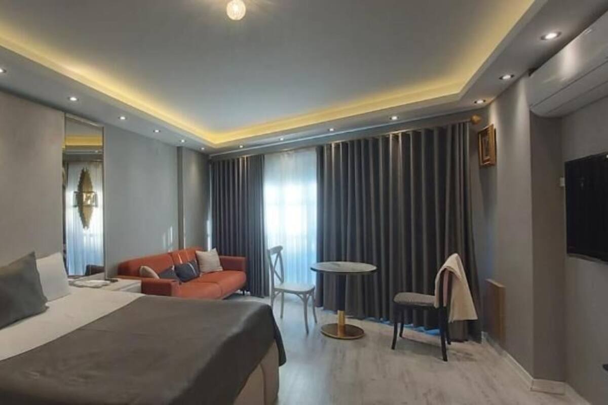 A modern hotel room with a large bed, a sofa, a small table, and a TV.