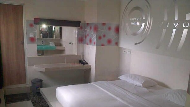 A hotel room with a bed, a small desk, a mirror, and a bathroom area. - Space Hotel by Papaho (Bogor)
