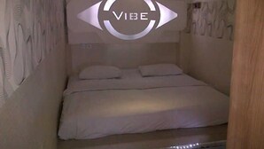 A bedroom with a bed, a headboard with a circular design, and a wall with a textured pattern. - Space Hotel by Papaho (Bogor)