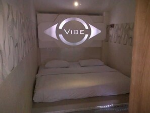 Une chambre à coucher avec un lit, une tête de lit au motif circulaire et un mur à motifs en relief.