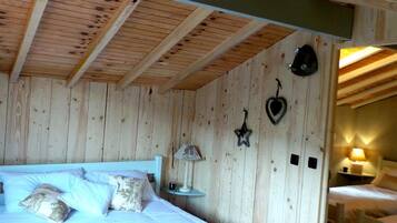 Dormitorio con paneles de madera, una cama, almohadas, una mesita de noche y decoración en la pared.