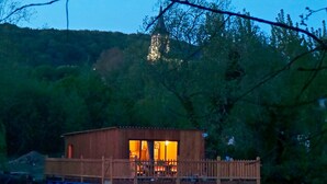 A wooden floating house with a deck and a large window, surrounded by water and trees. - Au Fil de L'eau (Colleville)